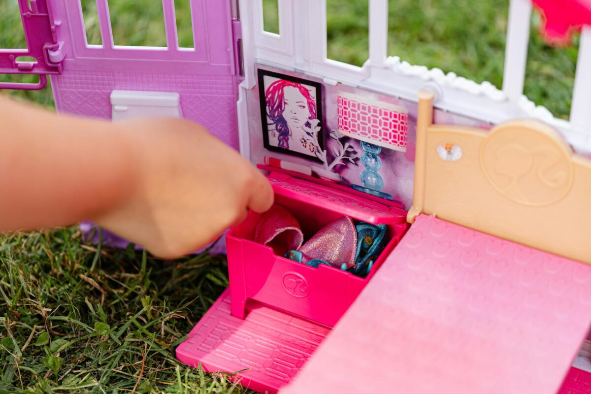 Child playing with a pink toy dollhouse